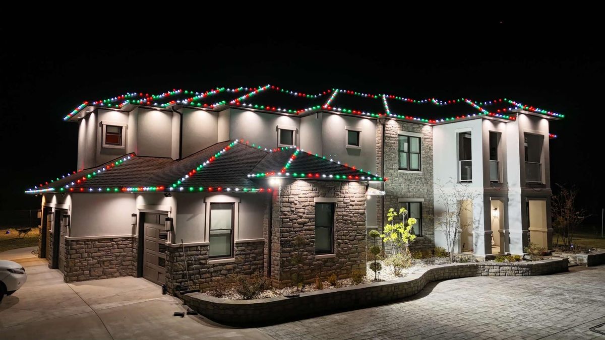 Two-story home with a red, white, and green roofline lighting pattern