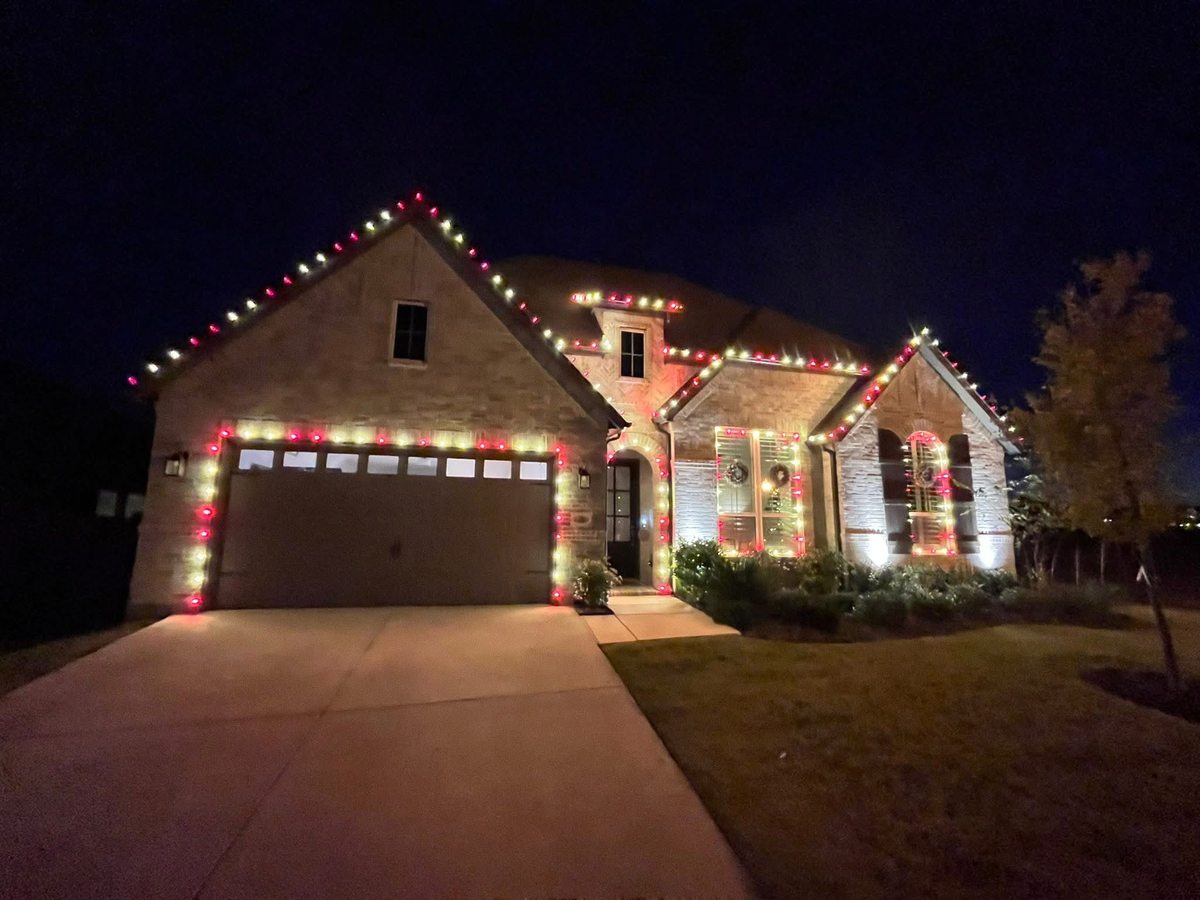 Home with red and warm white roofline lighting and lit garage trim